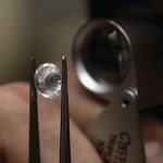 A diamond being inspected through a magnifying glass.