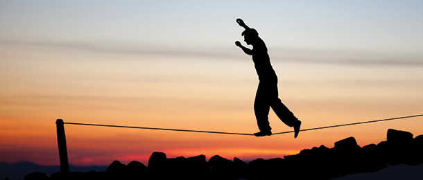 Person balances on a tightrope above the ground.